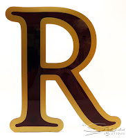 Photograph of burgundy flat cut acrylic letter with a gold vinyl border to create a two tone look.