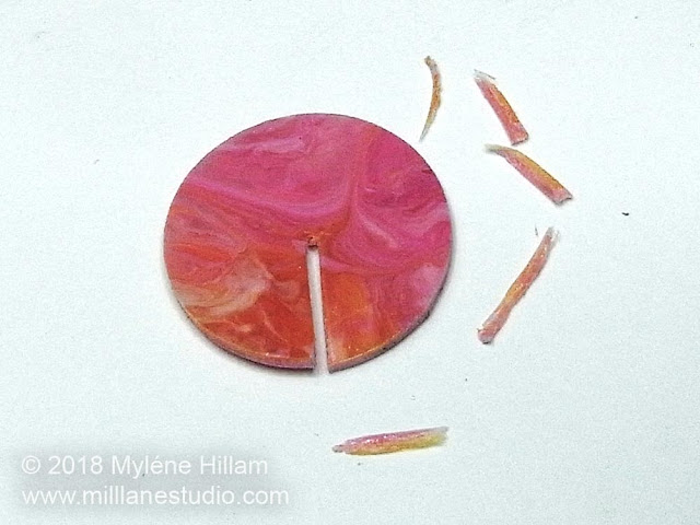 Marbled pink resin circle with a slit cut into it.