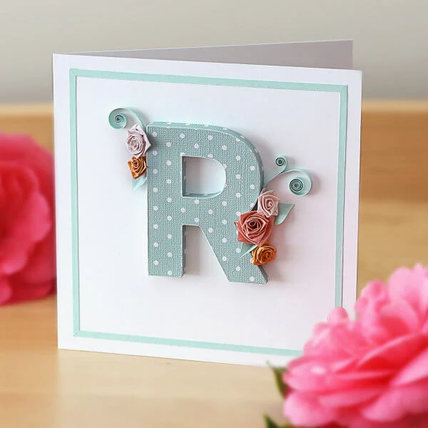 Dimensional paper uppercase letter R with quilled roses and scrolls on white card