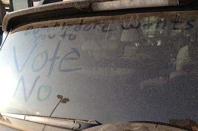 Dirty rear windshield of an SUV with hand written note in the dust, Dumbledore wants you to VOTE NO