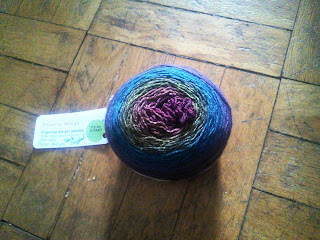 A cake of yarn ranging from dark blue to dark red.