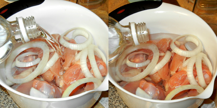 chicken and onions in a white bowl with vinegar being poured over them 