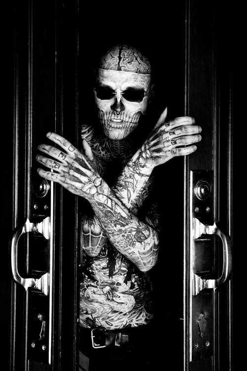 Hombre completamente tatuado estilo zombie saliendo de un sarcófago.
