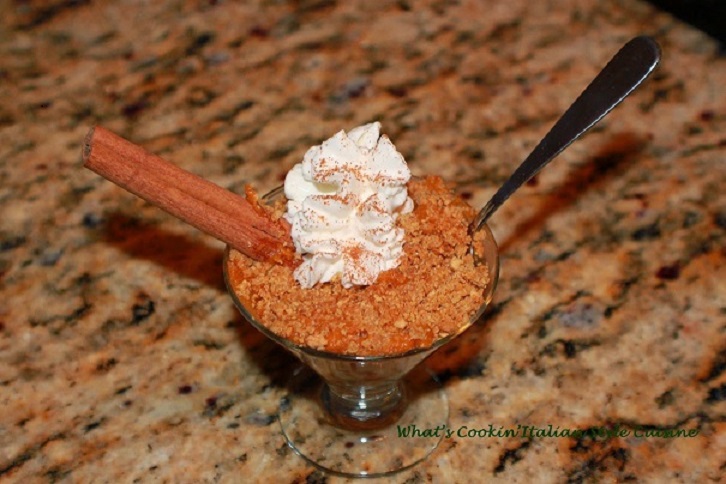 this is a rice pudding with pumpkin and spices cooking on the stove top then baked then garnished with whipped cream and cinnamon sticks and a dash or cinnamon and sugar on top