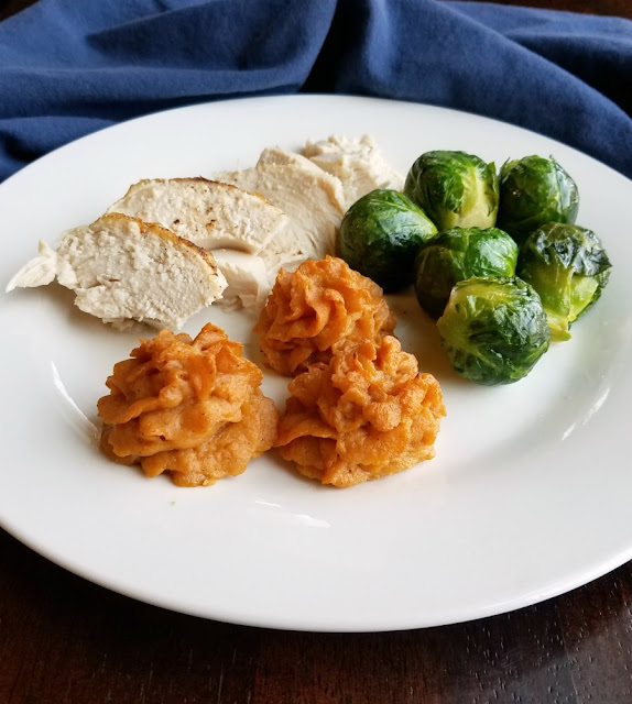 These duchess sweet potatoes add a little pizzazz to your plate, but they are really simple to make. They would be a fun way to change up your Thanksgiving or Christmas meal, but are delicious any time! plate with slices of roast chicken, roasted brussel sprouts and 3 ruffly duchess sweet potatoes