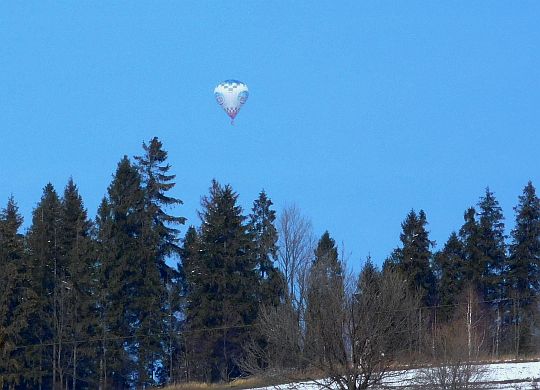Nad lasem widać balon niesiony prądami powietrza. Nad lasem widać balon niesiony prądami powietrza.