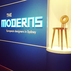 Entry to The Moderns exhibition, with a modernist chair in a display cabinet.
