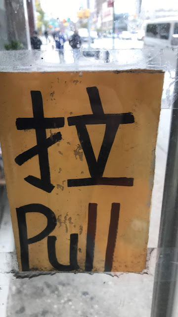 Pull (拉) A storefront door has a sign affixed to it in Mandarin Chinese and in English for "Pull"