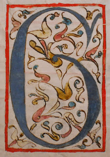 A floriated initial G in blue, red, and yellow.