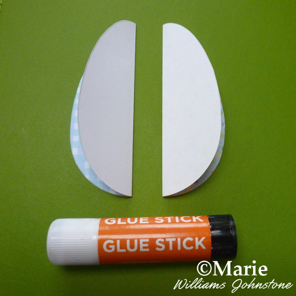 Using a glue stick to stick two folded paper eggs together