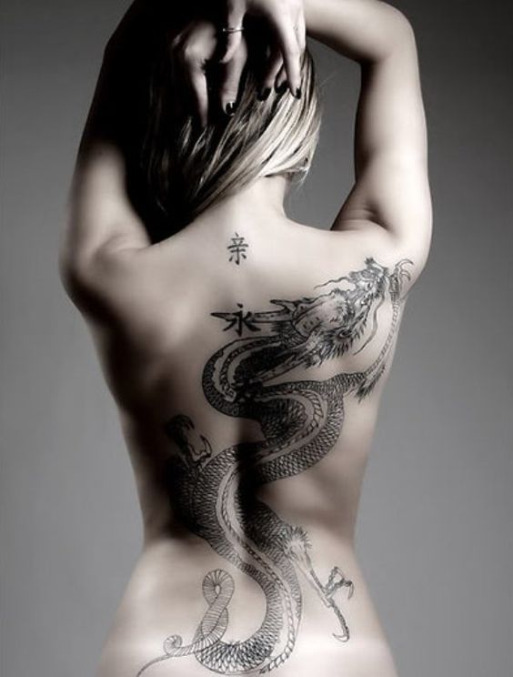 vemos a una mujer posando luce el tatuaje de un dragon