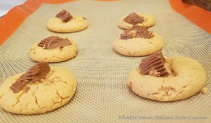 these keto baked peanut butter cookies are made with sugar free sweetener, sugar free peanut butter cups on top, sugar free peanut butter an egg baked on a silipat mat