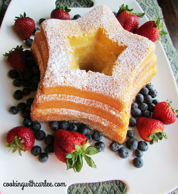 This Sand Torte was a fun cake to make! You won't believe the ingredients, there is a 1:1 ratio of flour to cornstarch! It is a simple cake, baked perfectly in a bundt pan. A European classic all dressed up for an American 4th of July in a star pan and served with strawberries and blueberries! platter with star shaped sand torte sprinkled with powdered sugar and surrounded with berries
