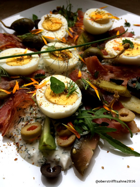  Eiersalat mit Oliven, gebratenem Frühstücksspeck, vielen Kräutern, Kapernäpfeln, Ruccola und Kräutersahne