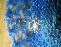 A close up view of a locking stitch marker with a silver crab charm.