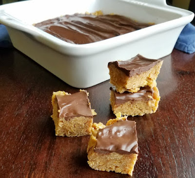 If a quick and easy chocolate peanut butter treat is what you meed, these corn flake bars are just the thing. They are the perfect mix of crunchy, chewy and delicious. small squares of chocolate peanut butter corn flake bars in front of pan of treats