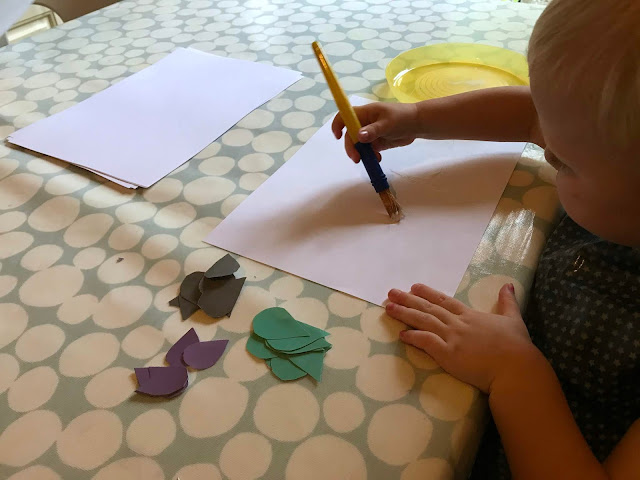 A toddler putting PVA glue on a white sheet of paper