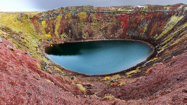 lago circular - água de cor verde - cercado de rochas de cor verde e vermelho escuro