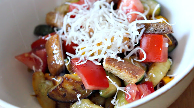 Pan-seared zucchini and yellow squash, in a bowl, topped with tomato, croutons and Parmesan cheese