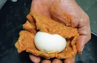 Egg is coated with minced chicken on palm of hand for scotch eggs recipe