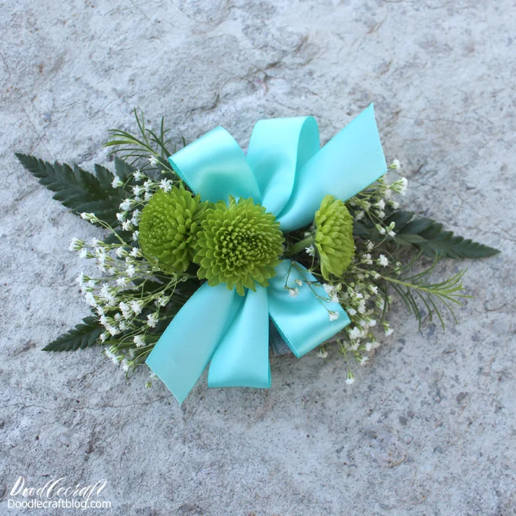 Fresh flowers and satin ribbon in aqua made into a wrist bouquet.