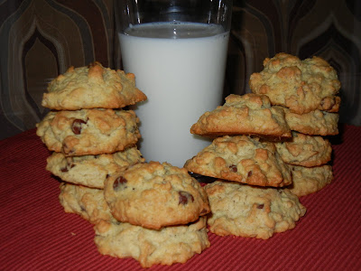 Oatmeal Chocolate Chip Cookies stacked around a cup of milk 