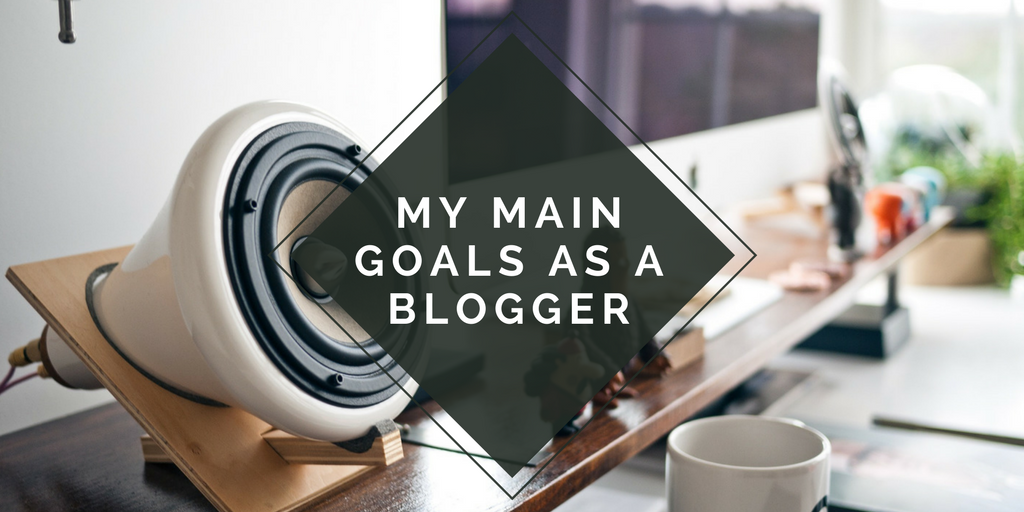 desk background with a blank triangle on top with the blog title "my main goals as a blogger"