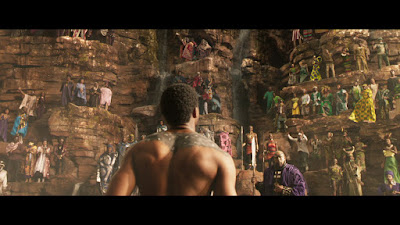It's a shirtless Chadwick Boseman staring at assorted Africans standing in rocks