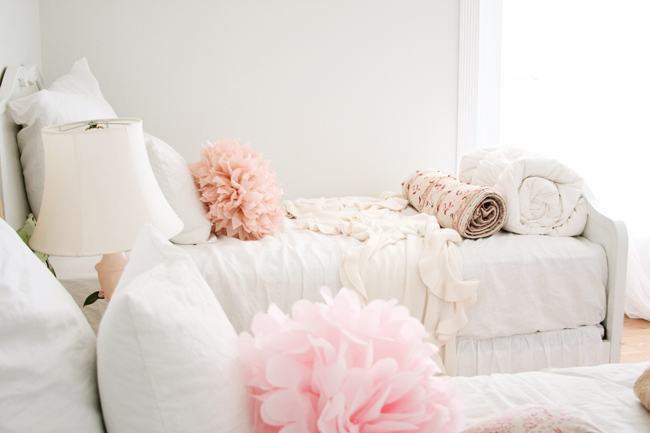 Romantic feminine farmhouse style in a girls bedroom with pink poufs on white linens #modernfarmhouse #Frenchfarmhouse #romanticbedroom