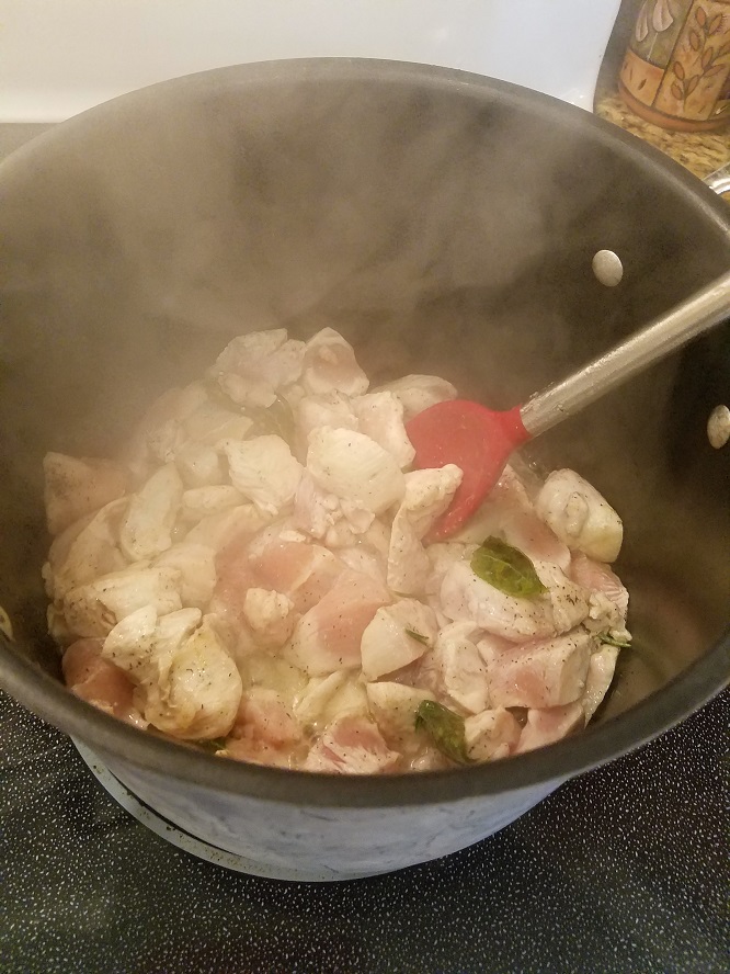 this is a pan of sauteed chicken with fresh basil,, fresh rosemary and garlic cooking until all the pink is gone for chicken and dumplings.