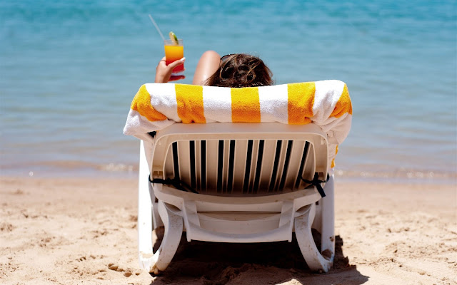 Vrouw op een ligstoel op het strand bij de zee