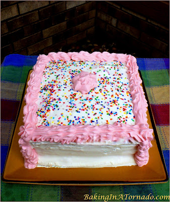 Lemon Raspberry Ice Cream Cake, two flavored cake layers, two ice cream layers and a crunchy center and frosted with whipped cream. A delicious summer treat. | Recipe developed by www.BakingInATornado.com | #recipe #dessert #cake