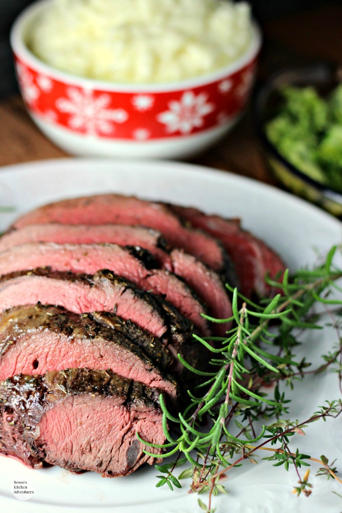 Garlic Herb Beef Tenderloin Roast with Creamy Horseradish Sauce | by Renee's Kitchen Adventures on white serving platter with a bowl of mashed potatoes in the background