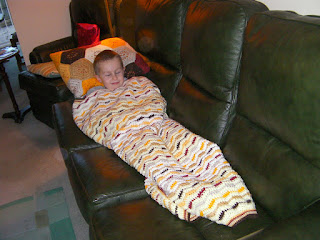 boy on sofa under woolly blanket