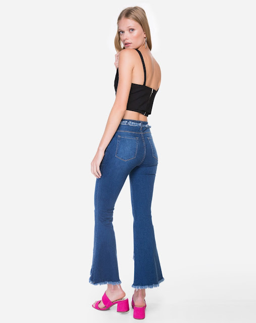 Calca jeans possui shape flare com barra transpassada, cintura alta e acabamento desfiado