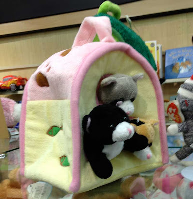 Three beanie babies with heads coming out of the wall of a pink and yellow tent-shaped bag