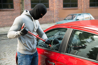 man breaking window of vehicle