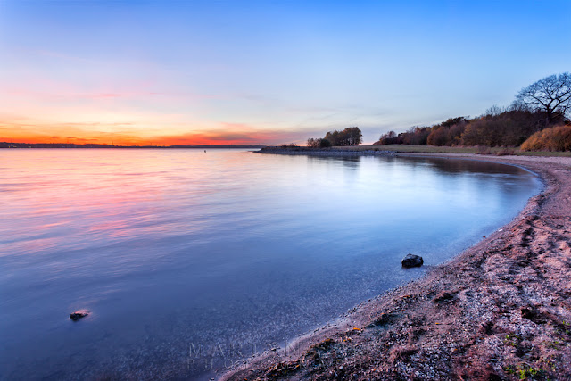Sunset glow over Grafham Water from the sandy shore Calm waters reflect the sunset light at Grafham Water in Cambridgeshire