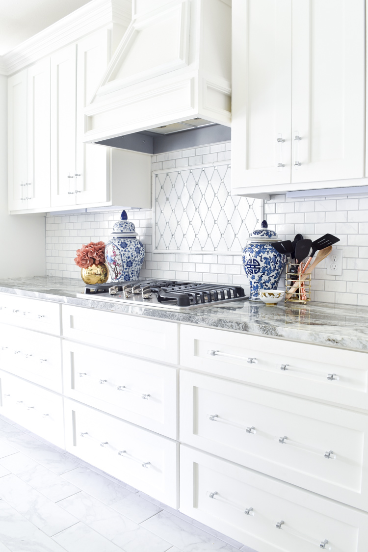 White shaker cabinet kitchen with marble countertops, blue and white ginger jars, and lucite cabinet hardware and pulls. #whitekitchen #brightkitchen #shakercabinets White shaker cabinet kitchen with marble countertops, blue and white ginger jars, and lucite cabinet hardware and pulls. #whitekitchen #brightkitchen #shakercabinets