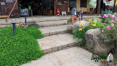 Piso de pedra com pedras rústicas sendo pedra folheta, pedra paralelepípedo e pedra rachão no tom de cor de pedra rosa. Piso de pedra nos patamares da escada com o paisagismo com pedras.