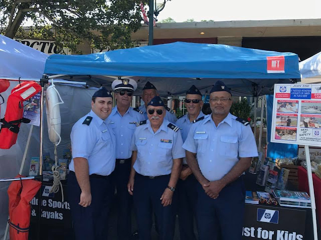 Six Auxiliarists stand prepared to answer questions about boating safety at a festival.