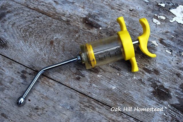 A yellow drench syringe on a wooden surface