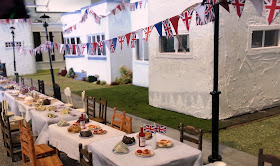Miniature scene of a VE Day street party in front of a row of Art Deco houses.