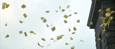 Hundreds of pieces of paper float down from the roof of an old school building.