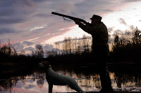 Bir ava nişan almış avcı ve yanındaki av köpeği