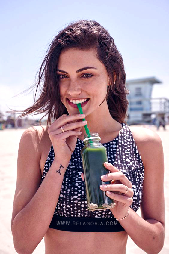 Foto de modelo risueña bebiendo un refresco, lleva tatuaje pequeño en muñeca