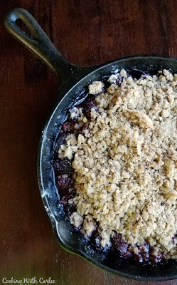 https://www.cookingwithcarlee.com/2015/10/maple-whipped-cream-guest-post-by-mimi.html close up of half of a cast iron skillet filled with blackberry crisp