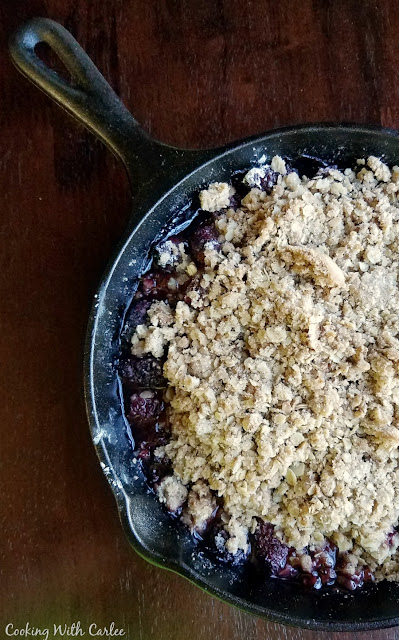 https://www.cookingwithcarlee.com/2015/10/maple-whipped-cream-guest-post-by-mimi.html close up of half of a cast iron skillet filled with blackberry crisp