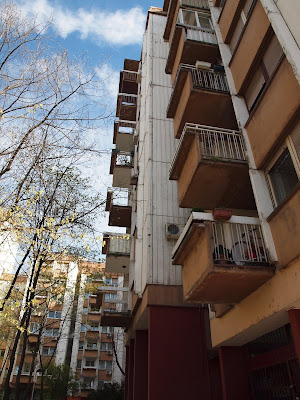 A series of bright yellow balconies on a brutalist apartment building against a bright blue sky