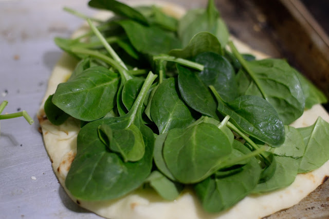 Fresh baby spinach on top of the naan bread. 
